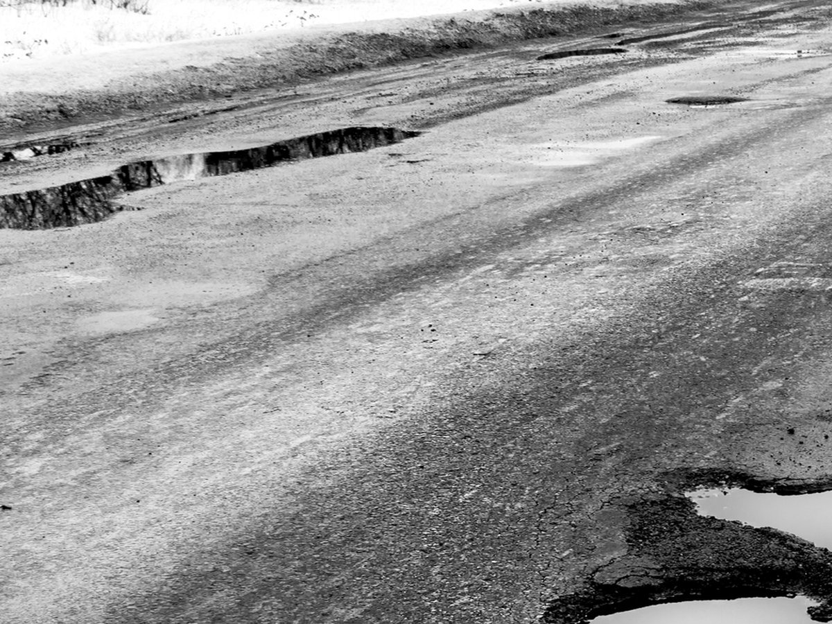 Sprungið slitlag með holuskemmdum, sú tegund skemmda sem glertrefjamottur eiga að fyrirbyggja